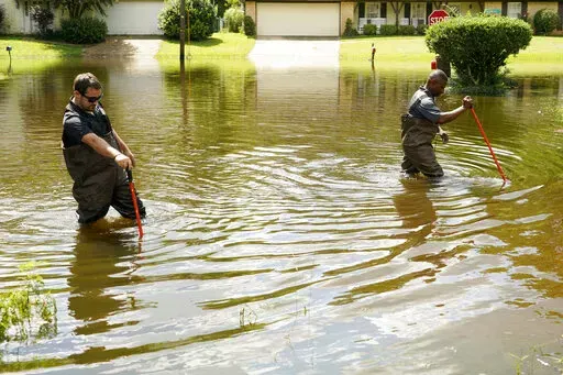 Hinds County Emergency Management Operations deputy director Tracy Funches, right, and operations coordinator Luke Chennault, wade through flood waters in northeast Jackson, Miss., on Aug. 29, 2022, as they check water levels. A federal agency has set aside money to help guard Mississippi’s capital city and surrounding areas against flood damage following two deluges in three years. The U.S. Army Corps of Engineers announced Monday, Oct. 3, 2022, that it has budgeted $221 million to help fund 