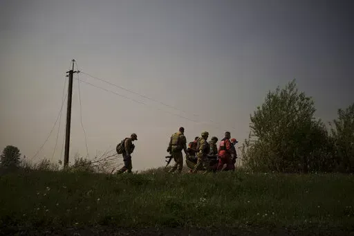 Ukrainian servicemen and emergency workers carry the body of a suspected Russian soldier in Malaya Rohan, a village retaken by Ukrainian forces on the outskirts of Kharkiv, Ukraine, Sunday, May 8, 2022. (AP Photo/Felipe Dana)