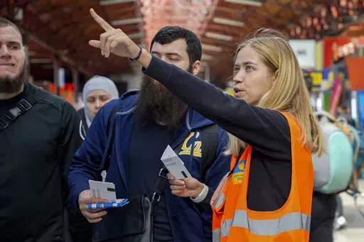 Ukrainian volunteer Anastasiia Haiduk points out at a departure board for Ukrainian refugees at Bucharest's North Railway Station in Romania, Saturday, April 23, 2022. Nearly 5.2 million Ukrainians have fled since Russia's invasion, most have entered countries on Ukraine's western border: nearly 2.9 million Ukrainians have fled to Poland, while 810,000 others have fled to Romania and 510,000 have crossed into Hungary since the war began.(AP Photo/Chisato Tanaka)
