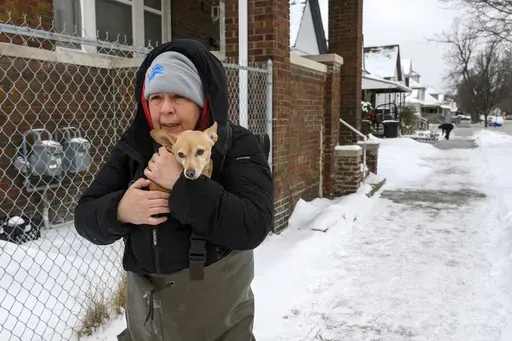 Lisa Muscat carries her dog Zoey to safety after a water main break in Detroit caused massive flooding, triggering evacuations, Monday, Feb. 17, 2025. (Andy Morrison/Detroit News via AP)