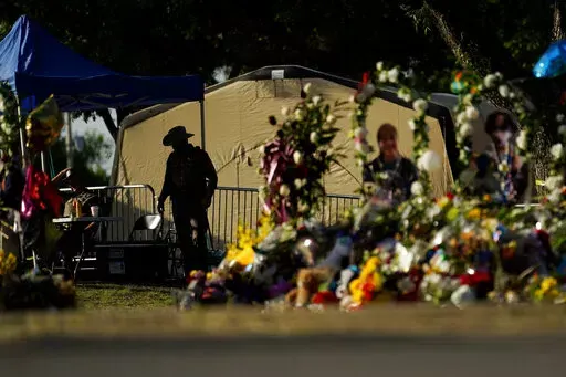 A Texas Department of Public Safety officer keeps watch on June 3, 2022, in Uvalde, Texas, near a memorial outside Robb Elementary School created to honor the victims killed in last a school shooting. As public pressure mounts for more information on the deadly Uvalde school shooting, some are concerned that Texas officials will use a legal loophole to block records from being released — even to the victims' families — once the case is closed. (AP Photo/Eric Gay, File)