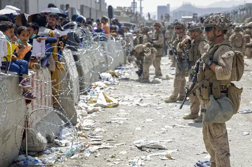 In this image provided by the U.S. Marines, U.S. Marines with Special Purpose Marine Air-Ground Task Force - Crisis Response - Central Command, provide assistance during an evacuation at Hamid Karzai International Airport in Kabul, Afghanistan, Aug. 20, 2021. More than a year after the Taliban takeover that saw thousands of Afghans rushing to Kabul's international airport amid the chaotic U.S. withdrawal, Afghans at risk who failed to get on evacuation flights say they are still struggling to fi