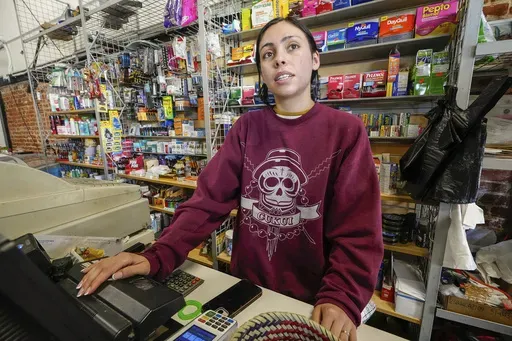 College student Jimena Sanchez, right, who studies children's development works as a part-time cashier earning minimum wage at a family store, in Los Angeles on Oct. 11, 2024. (AP Photo/Damian Dovarganes)