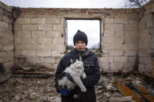 Danyk Rak, 12, holds a cat standing on the debris of his house destroyed by Russian forces' shelling in the village of Novoselivka, near Chernihiv, Ukraine, April 13, 2022. Danyk's family home was destroyed and his mother seriously wounded as Russian forces bombarded Kyiv’s suburbs and surrounding towns in a failed effort to seize the capital. (AP Photo/Evgeniy Maloletka, File)