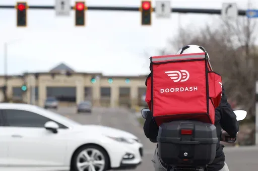 A food delivery rider waits for the traffic light to change Monday, March 30, 2020, in Lone Tree, Colo. (AP Photo/David Zalubowski, File)