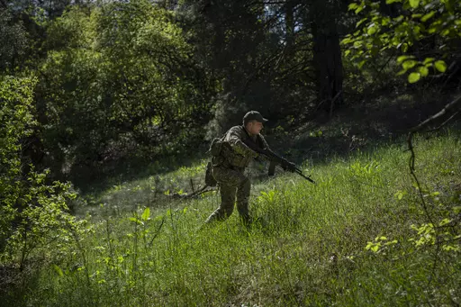 A Ukrainian Border Guard soldier participates in a military exercise in central Ukraine, Monday, May 1, 2023. Ahead of the much-anticipated Ukrainian counter-offensive, newly formed military assault units train in the country's dense forests. (AP Photo/Bernat Armangue)