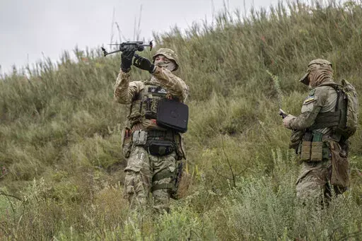 A volunteer soldier holds up a drone used to release explosives at a training area outside Kyiv, Ukraine, Saturday, Aug. 27, 2022. Some volunteers signed up to join a Chechen unit that fights alongside the Ukrainian military. Fighters from Chechnya, the Russian republic in the North Caucasus, are participating on both sides of the conflict in Ukraine, with pro-Kyiv volunteers loyal to Dzhokhar Dudayev, the late Chechen leader who headed the republic's drive for independence from Russia. (AP Phot