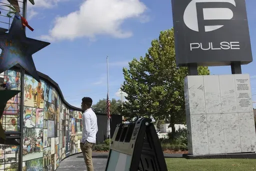 Brandon Wolf, a survivor of the Pulse nightclub shooting and activist, looks at the photos that are a part of the Pulse memorial in Orlando, Fla., on Sept. 9, 2022. (AP Photo/Cody Jackson, File)