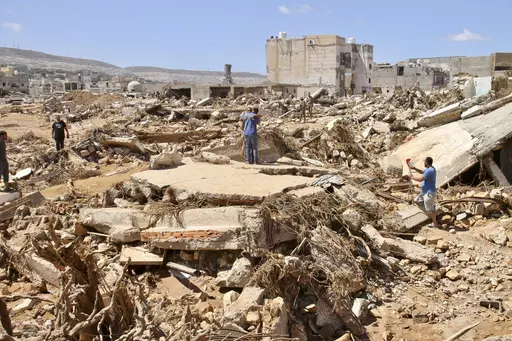Two men hug as people look for survivors in the flooded city of Derna, Libya, Wednesday, Sept.13, 2023. For many Libyans, the disastrous flooding that killed more than 11,000 people have fostered a sense of unity. The collective grief has morphed into a rallying cry of national unity in a country blighted by 12 years of conflict and division. (AP Photo/Yousef Murad, File)