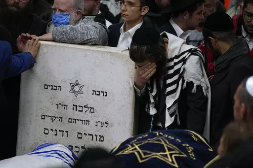 Mourners gather around the bodies of Israeli couple Eli Mizrahi and his wife, Natalie, victims of a shooting attack Friday in east Jerusalem, during their funeral at the cemetery in Beit Shemesh, Israel, early Sunday, Jan. 29, 2023. On Friday, a Palestinian gunman opened fire outside an east Jerusalem synagogue, killing the couple and another five people, including a 70-year-old woman, and wounding three others before he was shot and killed by police, officials say. It was the deadliest attack o