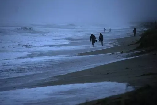 People walk along the oceanfront at Jensen Beach Park, where waves were reaching the dune's edge as conditions deteriorated with the approach of Hurricane Nicole, Nov. 9, 2022, in Jensen Beach, Fla. After months of gradually warming sea surface temperatures in the tropical Pacific Ocean, NOAA officially issued an El Nino advisory Thursday, June 8, 2023, and stated that this one might be different than the others. (AP Photo/Rebecca Blackwell, File)