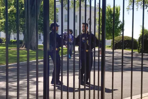 U.S. Secret Service uniformed division police officers carry a young child who crawled through the White House fence on Pennsylvania Avenue in Washington, Tuesday, April 18, 2023. The toddler earned the title of one of the tiniest White House intruders after he squeezed through the metal fencing on the north side of the executive mansion. Officers walked across the North Lawn to retrieve the child and reunite him with his parents on Pennsylvania Avenue. (AP Photo/Nancy Benac)