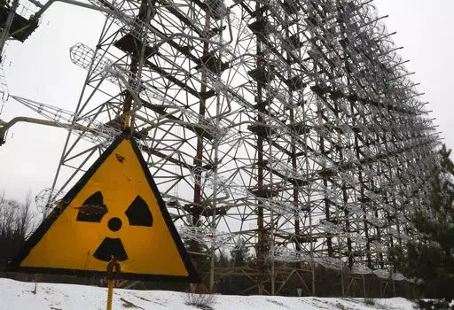 A Soviet-era top secret object Duga, an over-the-horizon radar system once used as part of the Soviet missile defense early-warning radar network, seen behind a radioactivity sign in Chernobyl, Ukraine, on Nov. 22, 2018. Among the most worrying developments on an already shocking day, as Russia invaded Ukraine on Thursday, was warfare at the Chernobyl nuclear plant, where radioactivity is still leaking from history's worst nuclear disaster 36 years ago. (AP Photo/Efrem Lukatsky, File)