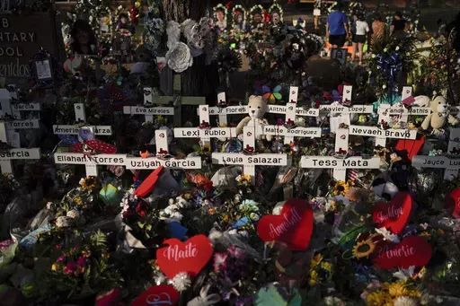 Flowers are piled around crosses with the names of the victims killed in a school shooting as people visit a memorial at Robb Elementary School to pay their respects May 31, 2022, in Uvalde, Texas. Families in Uvalde, Texas, are digging in for a new test of legal protections for the gun industry as they mark one year since the Robb Elementary School shooting. Both the U.S. government and gun manufacturers in recent years have reached large settlements following some of the nation's worst mass sh