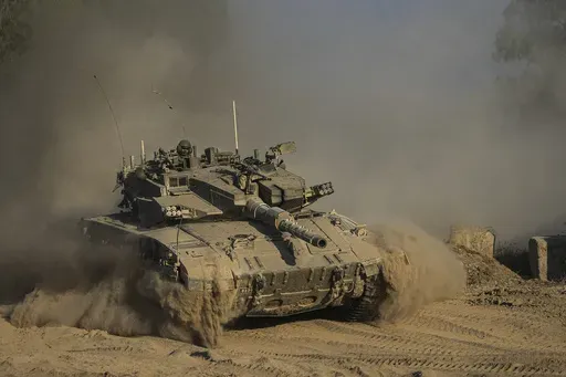 An Israeli soldier moves on the top of a tank near the Israeli-Gaza border, as seen from southern Israel, Sunday, July 14, 2024. (AP Photo/Tsafrir Abayov)