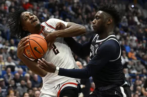UConn guard Tristen Newton, left, is fouled by Georgetown guard Jay Heath in the second half of an NCAA college basketball game, Sunday, Jan. 14, 2024, in Hartford, Conn. (AP Photo/Jessica Hill)