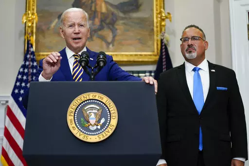 President Joe Biden speaks about student loan debt forgiveness in the Roosevelt Room of the White House, on Aug. 24, 2022, in Washington. Education Secretary Miguel Cardona listens at right. The White House is moving forward with a proposal that would lower student debt payments for millions of Americans now and in the future, offering a new route to repay federal loans under far more generous terms. Education Department officials on Tuesday, Jan. 10, 2023, called the new plan a “student loan 