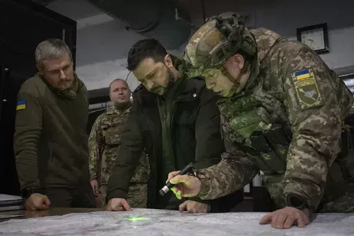 Ukrainian President Volodymyr Zelenskyy, Commander of Ukraine's Ground Forces Col.-Gen. Oleksandr Syrsky, right, and Roman Mashovets, deputy head of the Presidential Office, look at a map during their visit to the front-line city of Kupiansk, Kharkiv region, Ukraine, Thursday, Nov. 30, 2023. Zelenskyy says the war with Russia is in a new stage, with winter expected to complicate fighting after a summer counteroffensive that failed to produce desired results due to enduring shortages of weapons a