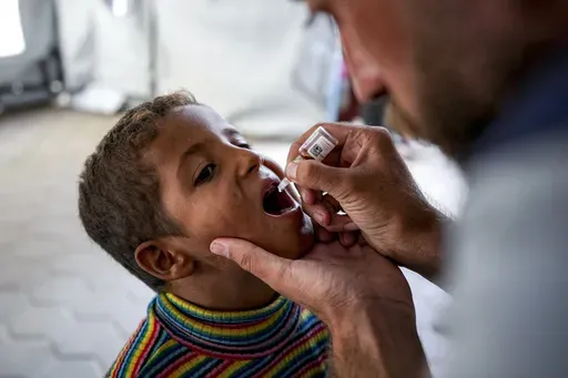 A health worker administers a polio vaccine to a child at a hospital in Deir al-Balah, central Gaza Strip, Sunday, Sept. 1, 2024. (AP Photo/Abdel Kareem Hana)