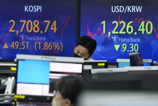 A currency trader watches monitors in front of screens showing the Korea Composite Stock Price Index (KOSPI) and the foreign exchange rate between U.S. dollar and South Korean won, right, at the foreign exchange dealing room of the KEB Hana Bank headquarters in Seoul, South Korea, Thursday, March 17, 2022. Asian stock prices have surged for a second day after the Federal Reserve announced its first interest rate hike since 2008 and China promised support for its real estate and internet industri