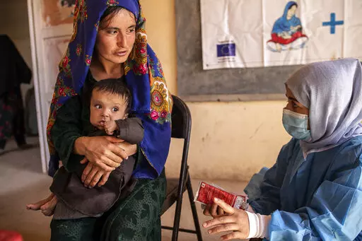A Save the Children nutrition counsellor, right, explains to Nelab, 22, how to feed her 11-month-old daughter, Parsto, with therapeutic food, which is used to treat severe acute malnutrition, in Sar-e-Pul province of Afghanistan, Thursday, Sept. 29, 2022. A senior U.N. official in Afghanistan met the deputy prime minister of the Taliban-led government to discuss a ban on women working for non-governmental groups. Save the Children is one of the major aid agencies that suspended its operations in
