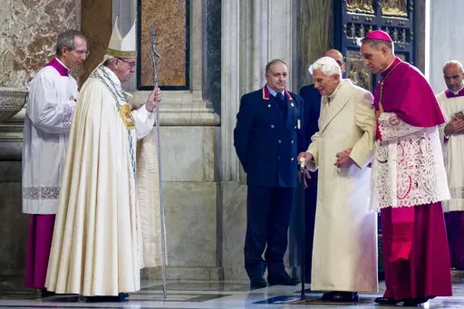 Pope Francis, second from left, watches Pope Emeritus Benedict XVI enter St. Peter's Basilica accompanied by Monsignor Georg Gaenswein, right, at the Vatican, on Dec. 8, 2015. Pope Benedict XVI's 2013 resignation sparked calls for rules and regulations for future retired popes to avoid the kind of confusion that ensued. Benedict, the German theologian who will be remembered as the first pope in 600 years to resign, has died, the Vatican announced Saturday Dec. 31, 2022. He was 95. (AP Photo/Andr