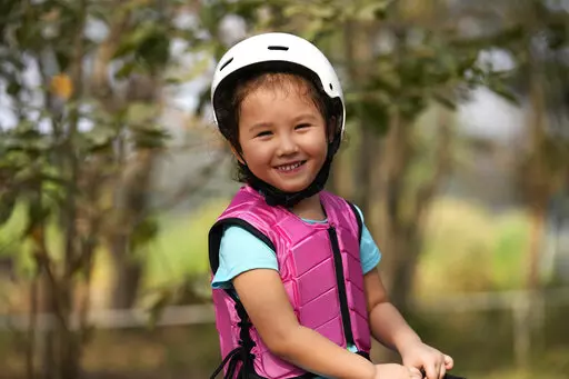 Rylae-Ann Poulin smiles as she learns to ride a horse in Bangkok, Thailand, Saturday, Jan. 14, 2023. Rylae-Ann was among the first to benefit from a new way of delivering gene therapy _ directly into the brain _ that experts believe holds great promise for treating a host of brain disorders. (AP Photo/Sakchai Lalit)