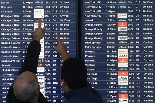 Two men point toward plane arrivals on a flight information board at San Francisco International Airport in San Francisco, Tuesday, Nov. 26, 2019.   Forecasters say, Friday, March 11, 2022,  a powerful, late-winter storm combining rivers of moisture and frigid temperatures is expected to dump snow from the Deep South all the way north to the Canadian border over the weekend that could cause travel problems and power outages across a wide part of the Eastern United States from late Friday through
