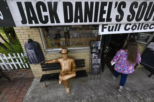 A statue of Jack Daniels sits on a bench as a visitor enters a souvenir shop in the town where the distillery is located Wednesday, June 14, 2023, in Lynchburg, Tenn. A destructive and unsightly black fungus which feeds on ethanol emitted by whiskey barrels has been found growing on property near the distillery's nearby barrelhouses which has resulted in a lawsuit against it. (AP Photo/John Amis)
