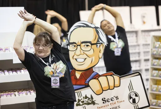 Michelle King of San Francisco does yoga in the See's Candies booth before the arrival of shareholders for the Berkshire Hathaway annual meeting on May 4, 2024, in Omaha, Neb. Berkshire Hathaway reports earnings on Saturday, Aug. 3, 2024. (AP Photo/Rebecca S. Gratz, File)