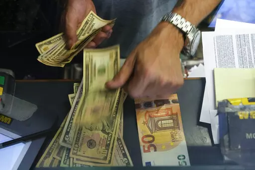 A cashier changes a 50 Euro banknote with US dollars at an exchange counter in Rome, Wednesday, July 13, 2022. The euro on Tuesday fell to parity with the dollar for the first time in nearly 20 years. (AP Photo/Gregorio Borgia)