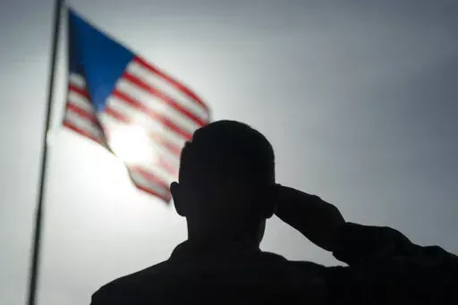 In this photo taken Aug. 26, 2019 and released by the U.S. Air Force, a U.S. Air Force Staff Sgt., salutes the flag during a ceremony signifying the change from tactical to enduring operations at Camp Simba, Manda Bay, Kenya. U.S. officials tell The Associated Press that military investigations have found that poor leadership, inadequate training and a "culture of complacency” among U.S. forces undermined efforts to fend off a 2020 attack by militants in Kenya that killed three Americans. (Sta