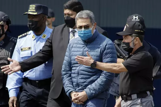 Former Honduran President Juan Orlando Hernandez, second from right, is taken in handcuffs to a waiting aircraft as he is extradited to the United States, at an Air Force base in Tegucigalpa, Honduras, April 21, 2022. Hernández has been convicted in New York, Friday, March 8, of charges that he conspired with drug traffickers, his military and police to enable tons of cocaine to make it unhindered into the United States. (AP Photo/Elmer Martinez, File)