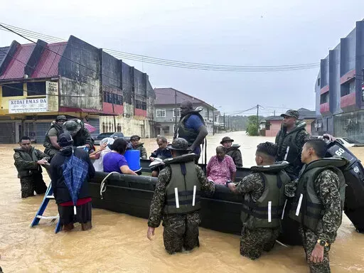 In this photo released by National Disaster Management Agency, the army evacuate residents on Chaah town in Segamat, in southern Johor state, Malaysia, Wednesday, March 1, 2023. Rescuers in boats plucked flood victims trapped on rooftops and hauled others to safety as incessant rain submerged homes and villages in parts of Malaysia, leading to over 26,000 people evacuated as of Thursday. (National Disaster Management Agency via AP)