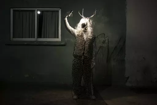 A man poses for a photo wearing a costume during a Muerteada parade in San Agustin Etla, Thursday, Nov. 2, 2023. Mexicans in the Oaxacan town celebrate the traditional Muerteada, a theatrical recreation that is performed through the night of November 1 until the early morning of the following day, with dances and music parading through the streets, while telling the story of how a deceased person is resurrected with the help of a priest, a doctor and a spiritist. (AP Photo/Maria Alferez)