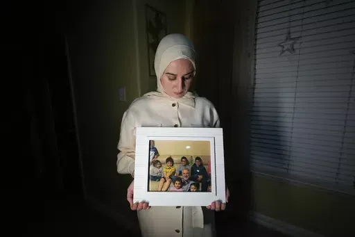 Maryam Kamalmaz hold a photo of her father with some of his 14 grandchildren in Grand Prairie, Texas, Jan. 17, 2024. U.S. officials have developed specific and highly credible intelligence suggesting that Majd Kamalmaz, an American citizen who disappeared seven years ago while traveling in Syria has died, Maryam Kamalmaz said Saturday, May 18. (AP Photo/Julio Cortez, File)