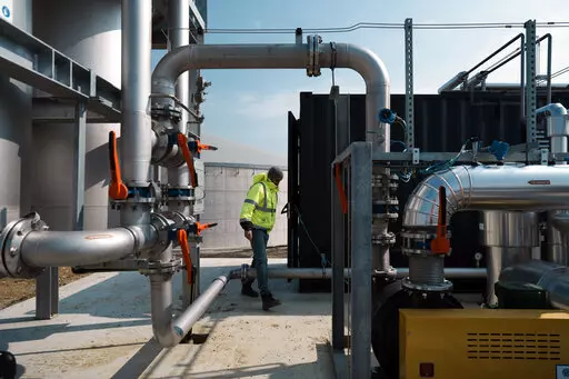 A worker walks among pipelines that will carry gas toward the city of Rambouillet, outside the village of Sonchamp, south of Paris, Tuesday, May 3, 2022.  In lush fields southwest of Paris, farmers are joining Europe’s fight to free itself from Russian gas. They’ll soon turn on a new facility where crops and waste are fermented to produce so-called “biogas.” (AP Photo/Thibault Camus)