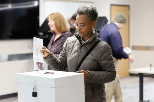 A woman places her ballot in a box during early voting in Waukesha, Wis., Tuesday, March 18, 2025. (AP Photo/Jeffrey Phelps)
