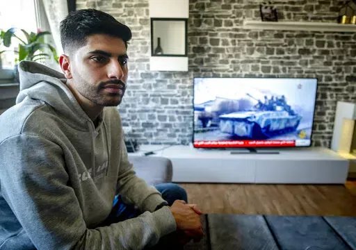 Orwa Staif, a Syrian student in the city of Kharkiv, sits on the sofa in the apartment of his parents in Nuremberg, Germany, Thursday, March 3, 2022. When Russia launched its war on Ukraine, Staif joined the exodus of people fleeing the onslaught. (AP Photo/Michael Probst)