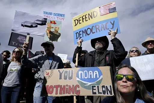 Susie House, front, and David Hill hold up signs as they join hundreds of others during a large rally and protest outside the National Oceanic and Atmospheric Administration campus Monday, March 3, 2025, in Boulder, Colo. (Helen H. Richardson/The Denver Post via AP)