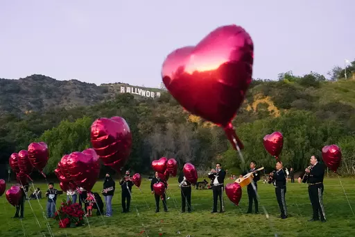 A Mexican Mariachi band surrounded by heart-shaped balloons awaits the arrival of a couple's wedding proposal ceremony at the Lake Hollywood Park in Los Angeles, on Feb. 14, 2022. This is the first Valentine's Day since the U.S. surgeon general issued a public health advisory declaring loneliness and isolation an epidemic with dire consequences. (AP Photo/Damian Dovarganes, File)