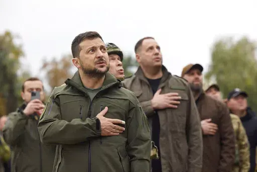 In this photo provided by the Ukrainian Presidential Press Office, Ukrainian President Volodymyr Zelenskyy, center, sings Ukrainian national anthem during his visit in Izium, Kharkiv region, Ukraine, Wednesday, Sept. 14, 2022. Ukrainian troops piled pressure on retreating Russian forces Tuesday, pressing deeper into occupied territory and sending more Kremlin troops fleeing ahead of the counteroffensive that has inflicted a stunning blow on Moscow's military prestige.(Ukrainian Presidential Pres