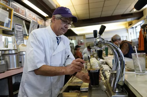 John Philis, a third-generation owner of the Lexington Candy Shop, prepares a Coke float at the luncheonette, Thursday, Sept. 28, 2023, in New York. The old school business met the new world when Nicolas Heller, a TikToker and Instagrammer with 1.2 million followers, popped in for a traditional Coke float. Naturally, he made a video. It went viral, garnering 4.8 million likes. (AP Photo/Mary Altaffer)