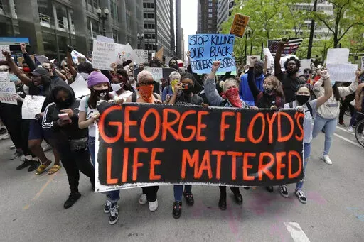 Protesters hold signs as they march during a protest over the death of George Floyd in Chicago on May 30, 2020. Two former Minneapolis police officers charged in Floyd's death are heading to trial on state aiding and abetting counts, the third and likely final criminal proceeding in a killing that mobilized protesters worldwide against racial injustice in policing. (AP Photo/Nam Y. Huh, File)