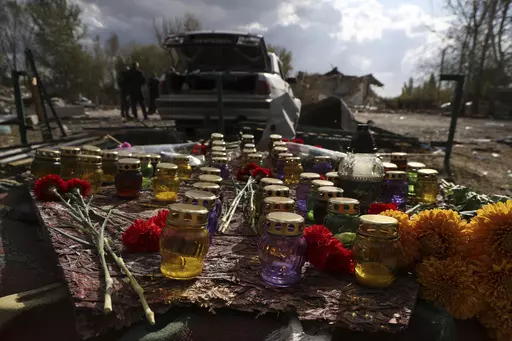 A memorial made with candles and flowers, which were brought by local residents, in the village of Hroza near Kharkiv, Ukraine, Friday, Oct. 6, 2023. Ukrainian officials say at least 51 civilians were killed in a Russian rocket strike on a village store and cafe in the eastern part of the country in one of the deadliest attacks in recent months. (AP Photo/Alex Babenko)