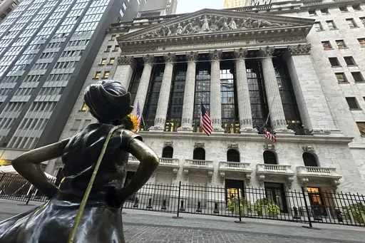 The Fearless Girl statue, with a flower draped on the shoulder, stands outside the New York Stock Exchange on Oct. 23, 2024. (AP Photo/Peter Morgan, File)