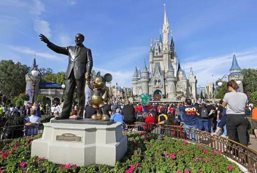 In this Jan. 9, 2019, photo, guests watch a show near a statue of Walt Disney and Micky Mouse in front of the Cinderella Castle at the Magic Kingdom at Walt Disney World in Lake Buena Vista, part of the Orlando area in Fla. Florida’s Republican Gov. Ron DeSantis' decision to punish Disney World, took his fighter mentality to a new level. In retribution for Disney's criticism of a new state law condemned by critics as “Don't Say Gay,” DeSantis signed legislation on Friday, April 23, 2022, s