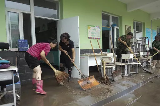 In this photo released by Xinhua News Agency, teachers clean classrooms at a school in the aftermath of flood waters from an overflowing river in Qizhongkou Town of Laishui County in north China's Hebei Province on Aug. 11, 2023. A vast swath of northeastern China is threatened by flooding as at least 90 rivers have risen above warning levels and 24 have already overflowed their banks. State media say crews are standing by to defend homes and farmland across the Songliao Basin north of Beijing w