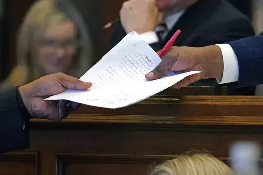 Mississippi Senate Press Secretary Arnold Lindsay, right, receives a resolution from a senator at the Mississippi Capitol in Jackson, Miss., Wednesday, Feb. 23, 2022. (AP Photo/Rogelio V. Solis)