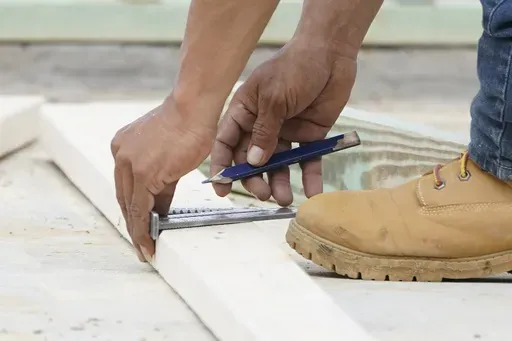 A workman measures a a piece of wood in Madison County, Miss., on March 16, 2021. Nearly one in three Americans earn money on the side in addition to working full time, a Bankrate survey found. (AP Photo/Rogelio V. Solis, File)